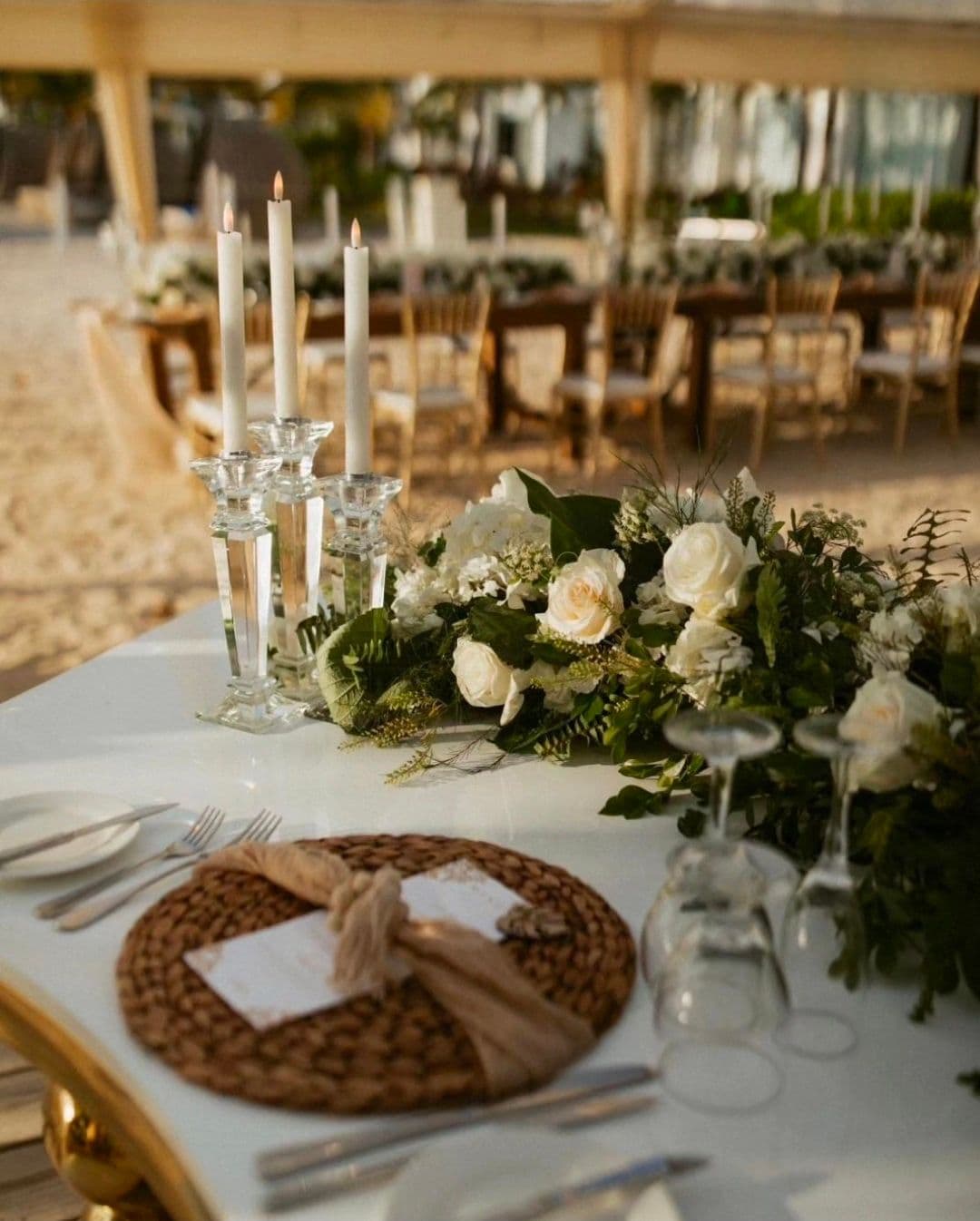 White and gold reception tablescape with candles, florals, and glassware